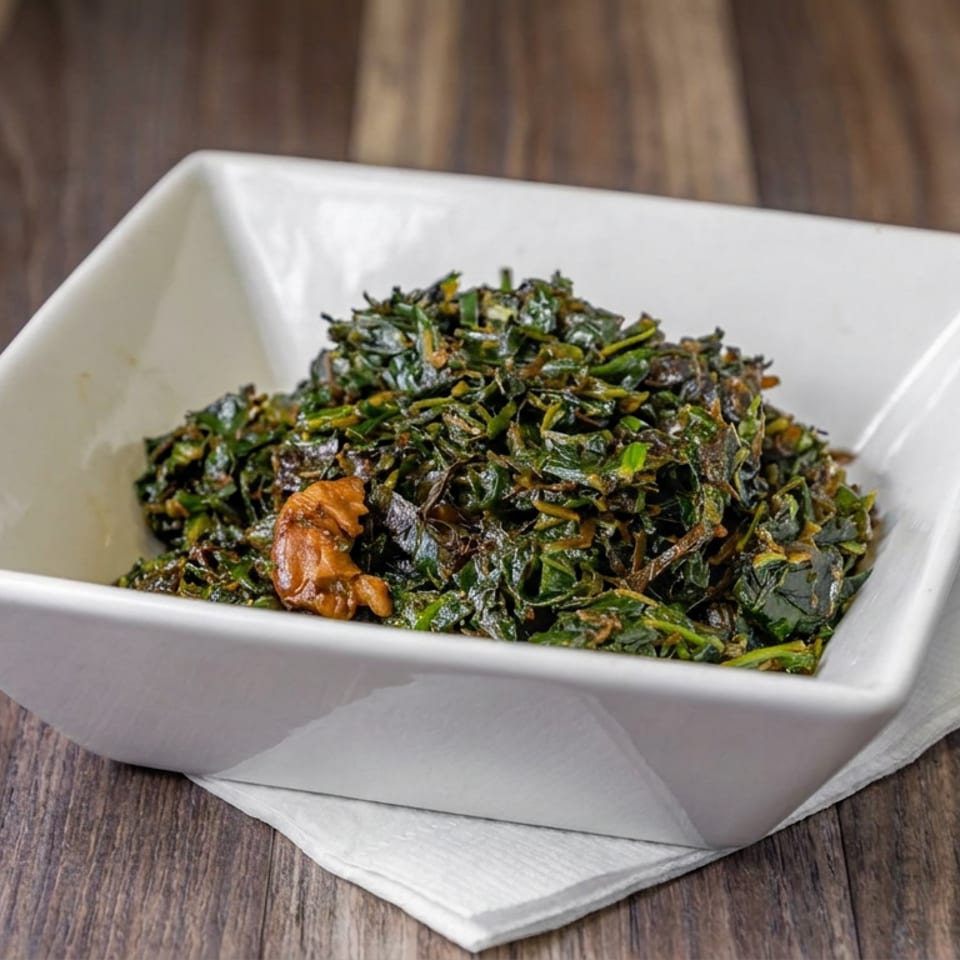 Seasoned sautéed greens with a visible shrimp served in a white bowl on a wooden table.